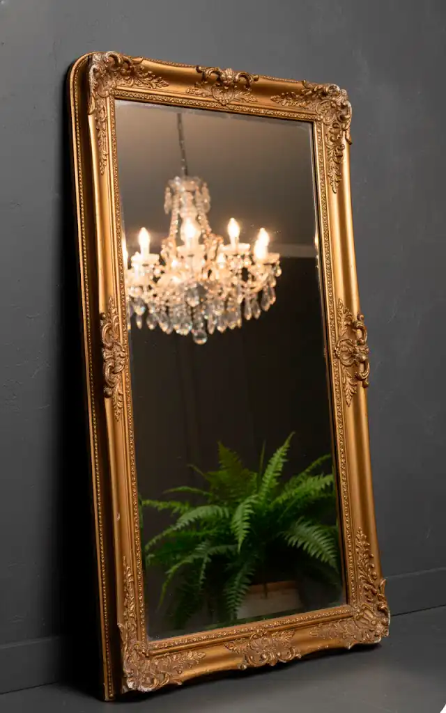 7 a vertical close up of a vintage style gold mirror leaning against a dark wall reflections of a chandelie 01 filled