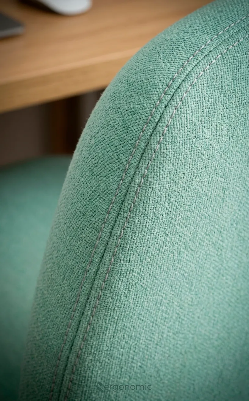 Close-up of soft mint upholstery fabric on a modern office chair.