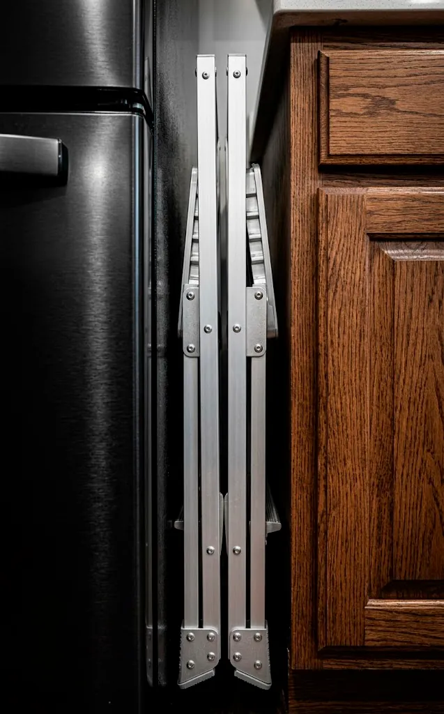 Slim aluminum step stool folded and stored in a narrow gap in a van.