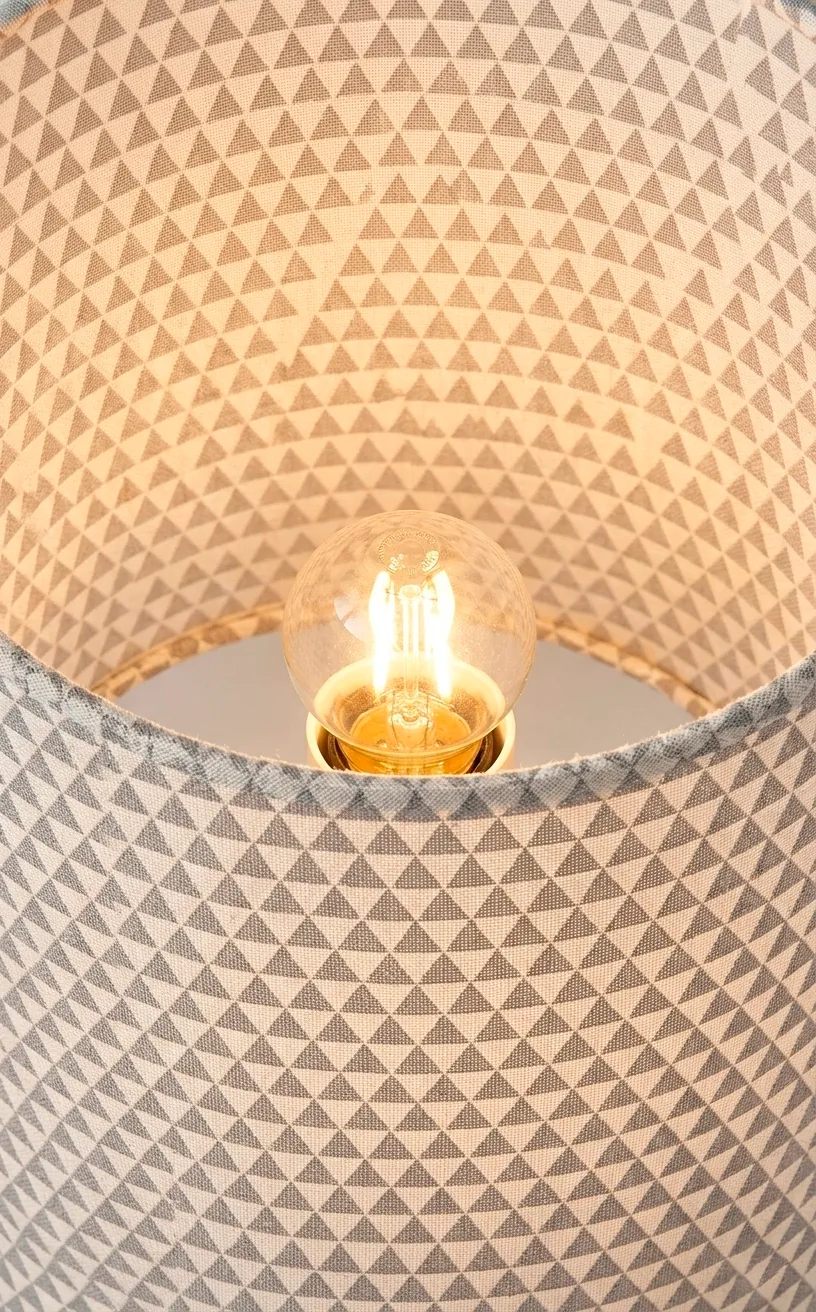 Close-up of a lit table lamp with a geometric triangle pattern on the shade.