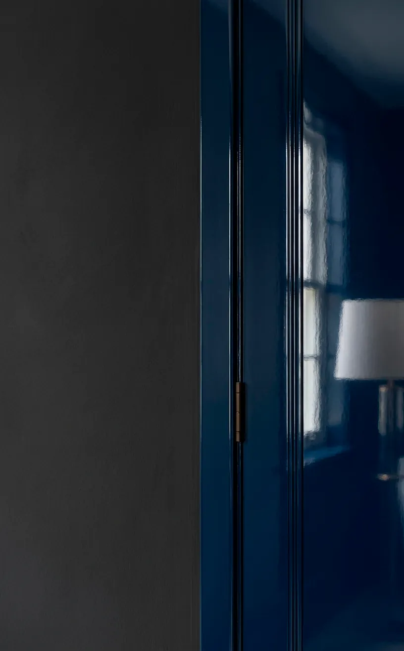 Detail of high-gloss navy trim against a matte charcoal bedroom wall.