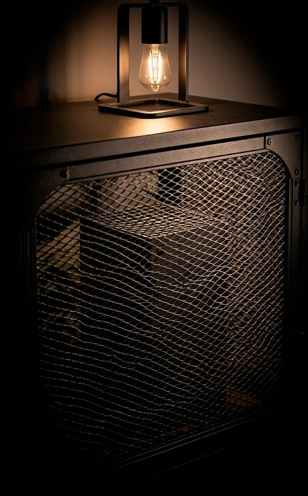 Close-up of matte black metal mesh door on an industrial wall-mounted media unit.