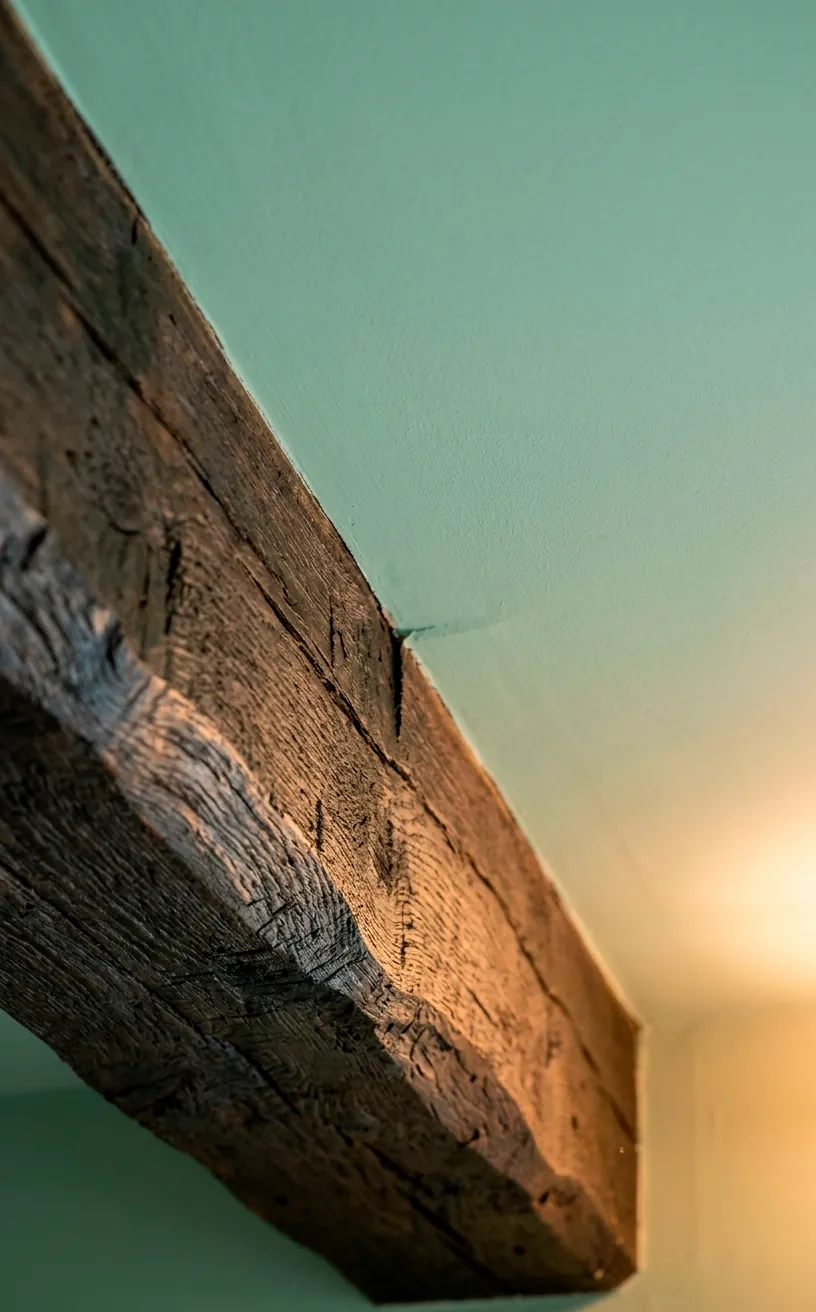 Close-up of a natural oak beam against a soft mint painted ceiling panel.