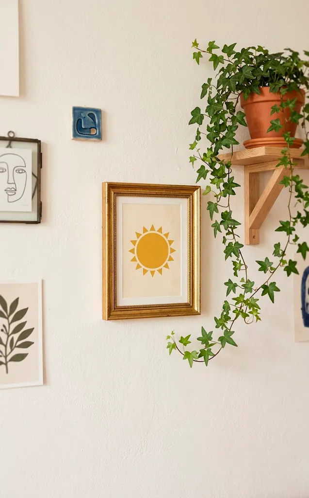 Small wall gallery with mustard yellow sun art and a trailing plant.