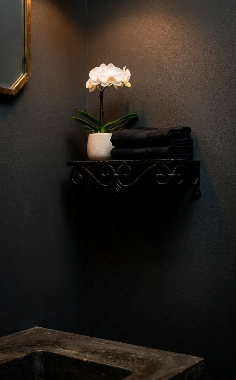 Close-up of black powder room decor featuring an orchid and dark linen towels against matte walls.