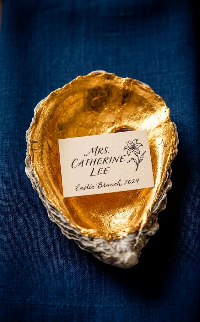 Gold oyster shell place card holder on a navy napkin.