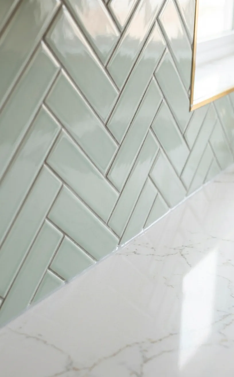 Close-up of white herringbone wall tiles and a smooth quartz countertop edge.