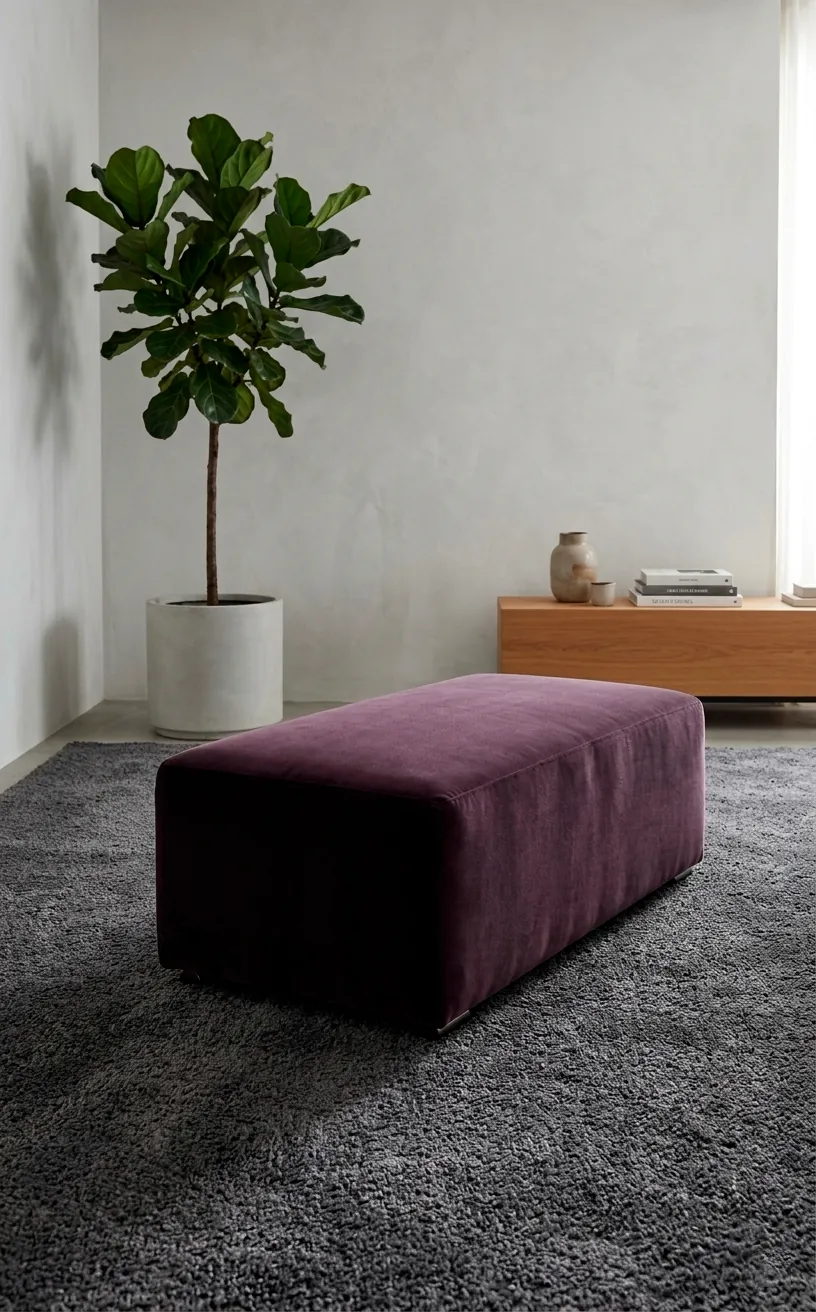 Plum velvet ottoman as a statement piece on a charcoal rug.