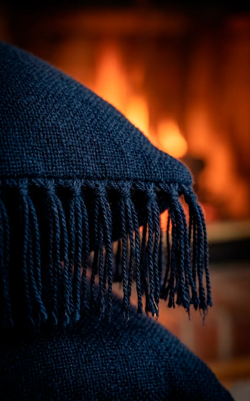 Close up of navy blue fringe trim on the edge of a velvet decorative pillow.