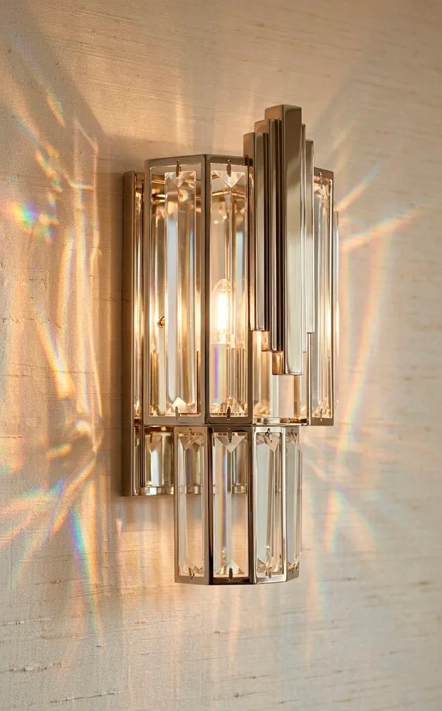 Art Deco crystal wall sconce detail showing light refraction on a textured bathroom wall.