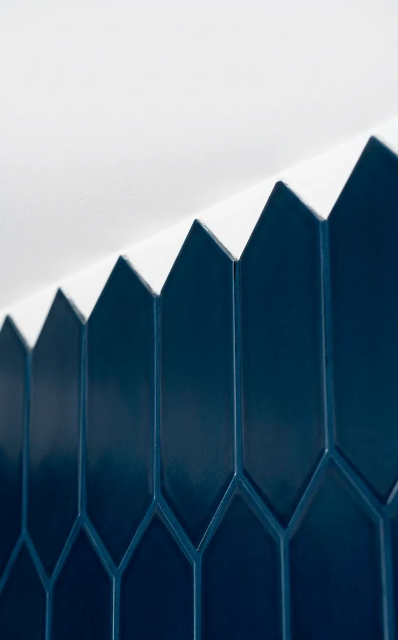 Macro shot of navy picket tiles and white grout against a clean white ceiling edge.