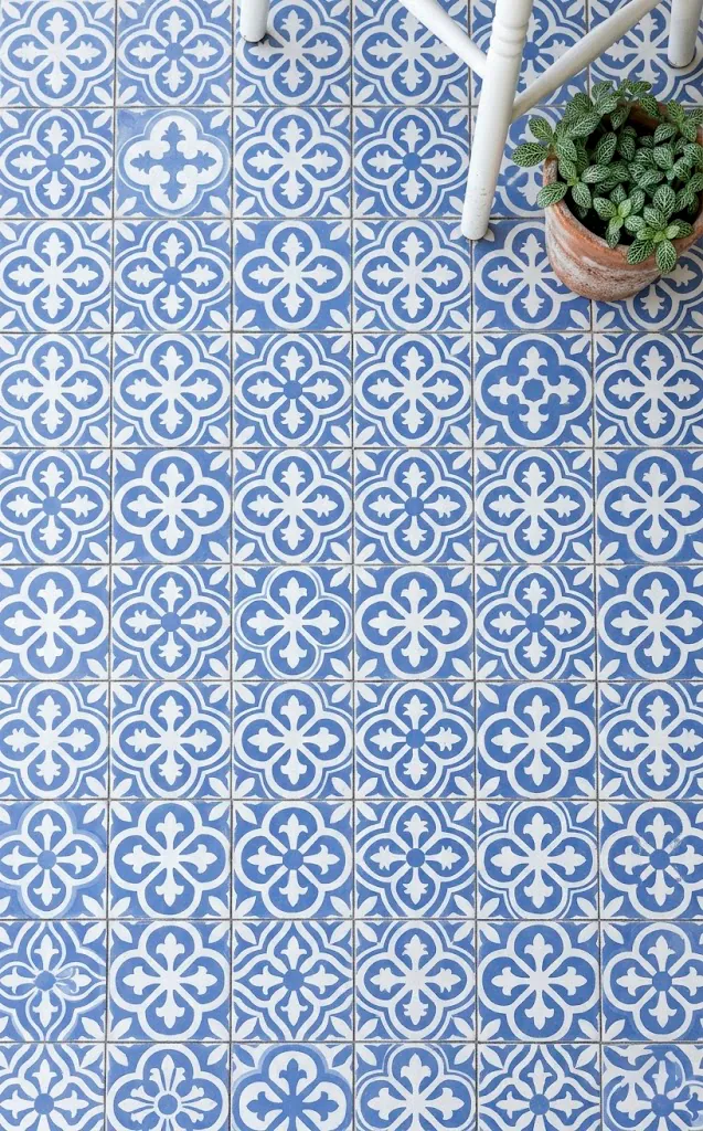 Periwinkle and white patterned floor tiles on a sunlit garden porch.