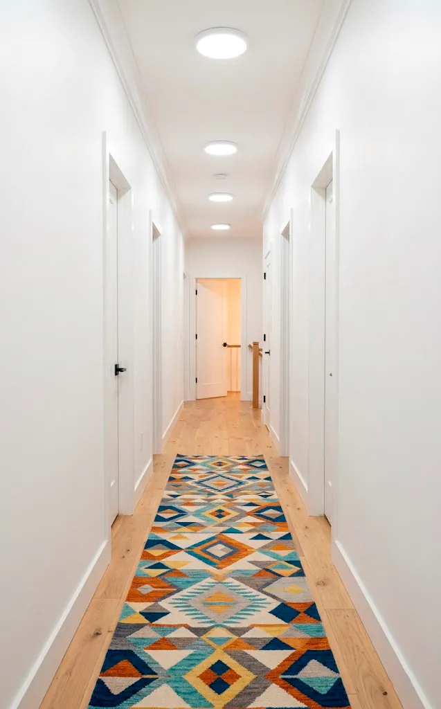 Sherwin Williams Pure White windowless entryway illuminated by modern LED lighting with a colorful runner rug.