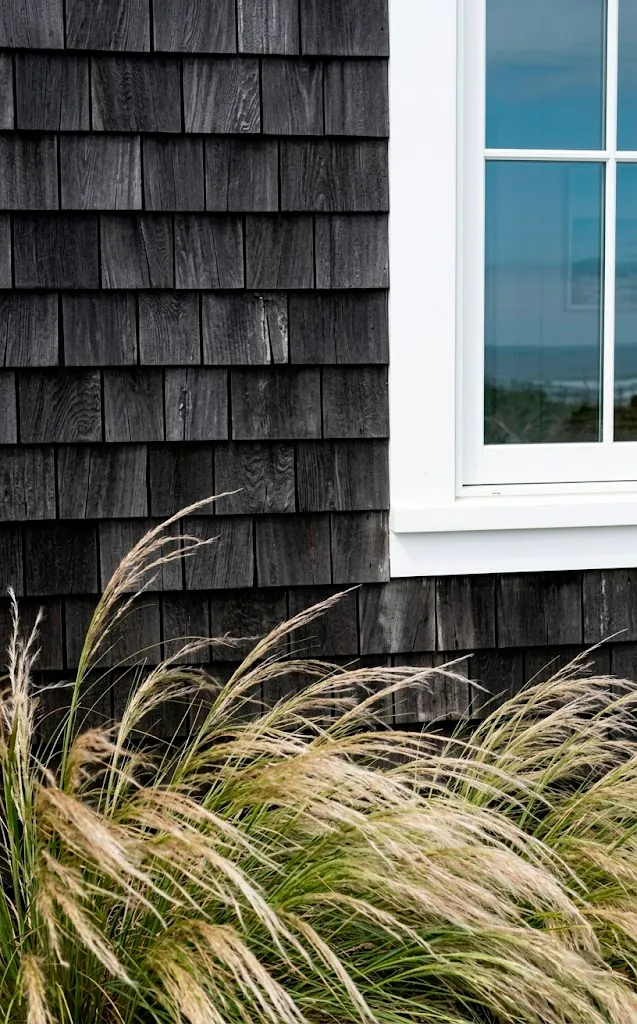 Charcoal black cedar shake siding texture with white window trim and coastal vibes.