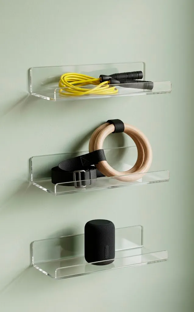 Transparent acrylic floating shelves holding a colorful jump rope and speaker in a gym.