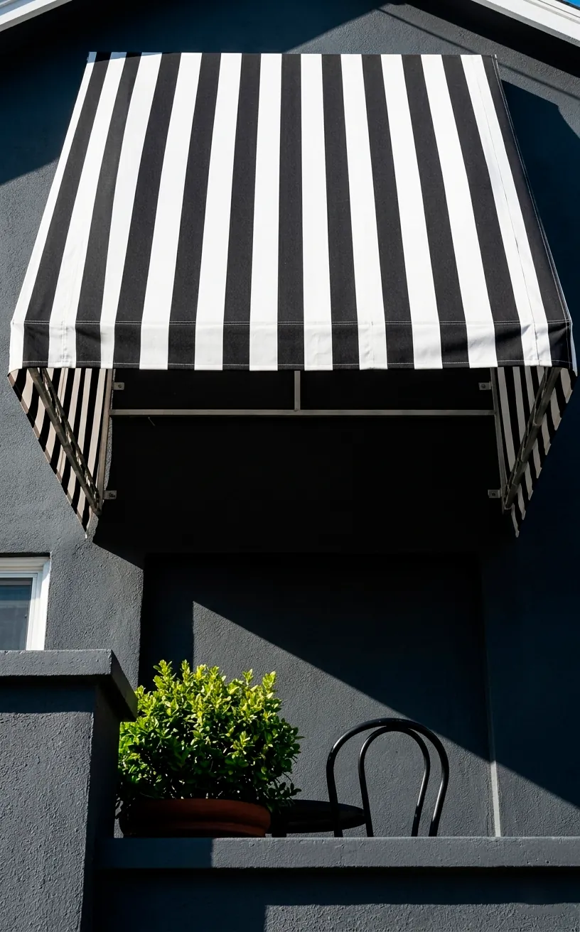 Black and white striped retractable fabric awning over a cozy front porch setup.