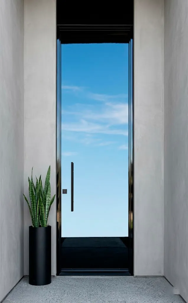 High-gloss black front door with sky reflections and minimalist gray walls.