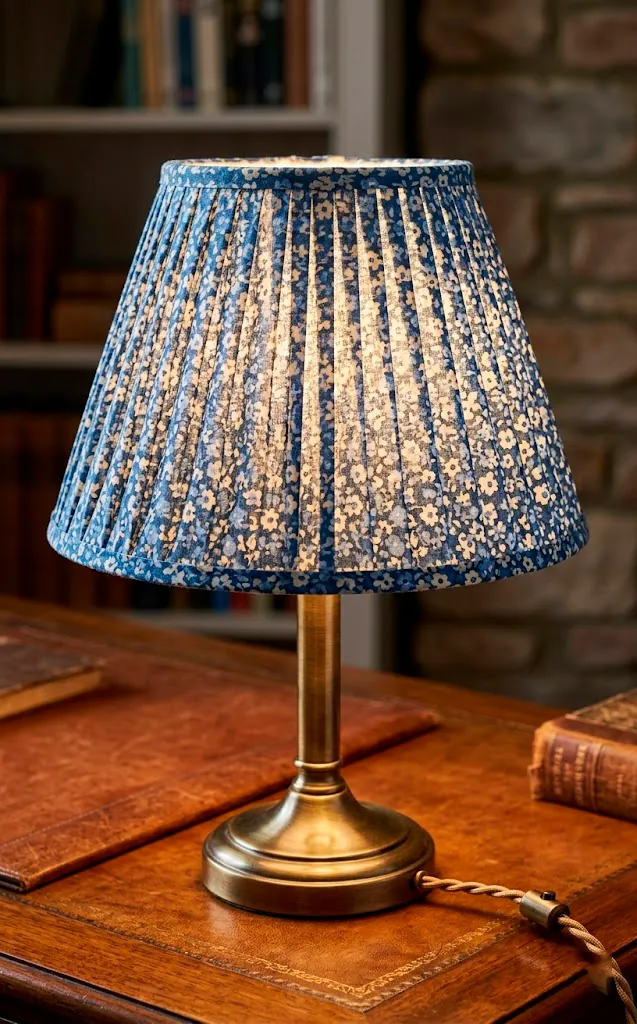 Brass table lamp with a blue pleated floral fabric lampshade.