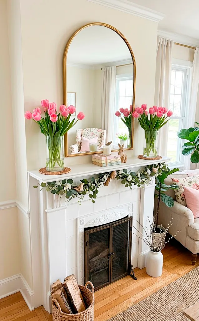 Spring-styled fireplace mantle with symmetrical clear glass vases filled with pink tulips.