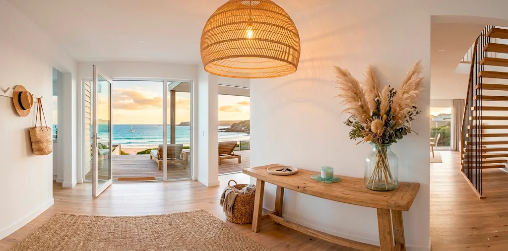 Large woven rattan pendant light hanging in a bright coastal style entryway above a reclaimed wood console table.